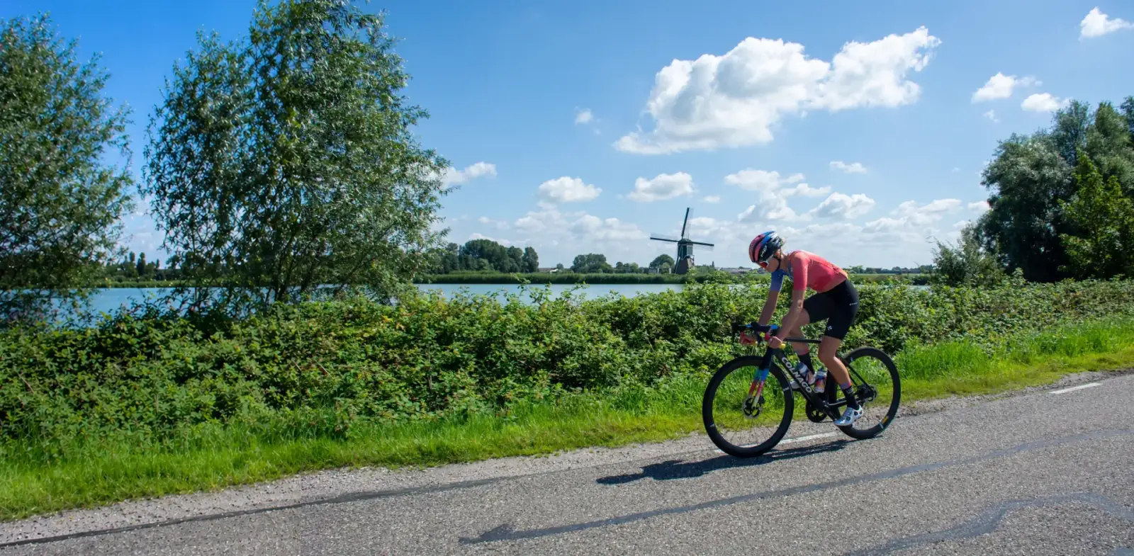 Cyclist riding past a Dutch windmill, online bike fitting in real-world conditions
